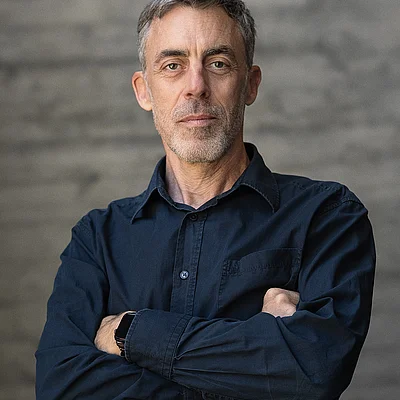 Portrait von Uwe Raabe, Geschäftsführer Technik, vor einer grauen Sichtbetonwand