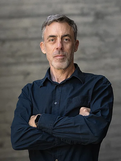 Portrait von Uwe Raabe, Geschäftsführer Technik, vor einer grauen Sichtbetonwand