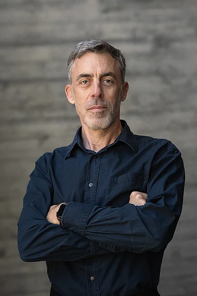 Portrait von Uwe Raabe, Geschäftsführer Technik, vor einer grauen Sichtbetonwand