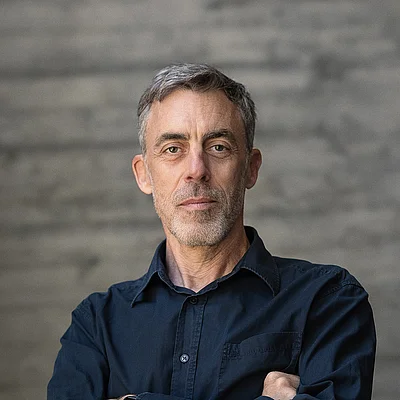 Portrait von Uwe Raabe, Geschäftsführer Technik, vor einer grauen Sichtbetonwand
