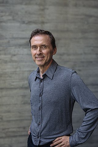 Portait von Inhaber Alwin Roppert vor einer Sichtbetonwand