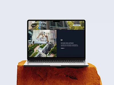 Laptop auf einem Felsblock vor hellem Hintergrund, auf dem Bildschirm die moderne Website von Vollack mit nachhaltiger Architektur, Stadtgrün und einem Menschen mit VR-Brille, ergänzt durch den Slogan „Die Zeichen stehen auf Zukunft.“