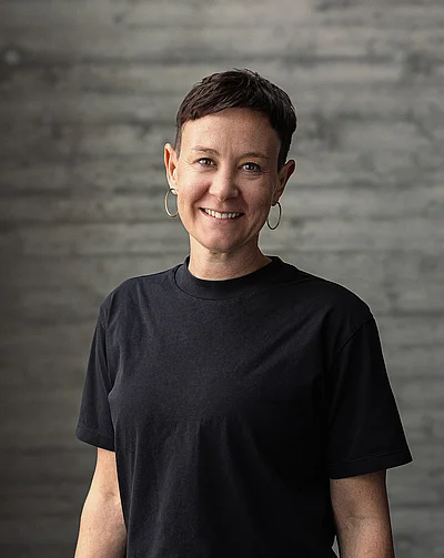Portrait von Katharina, Teamlead Social, vor einer grauen Sichtbetonwand