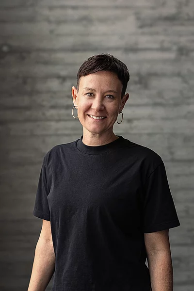 Portrait von Katharina, Teamlead Social, vor einer grauen Sichtbetonwand