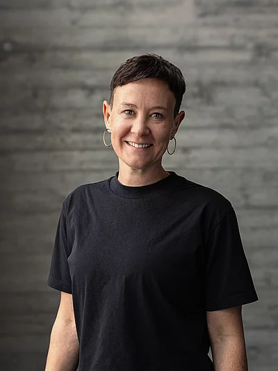 Portrait von Katharina, Teamlead Social, vor einer grauen Sichtbetonwand