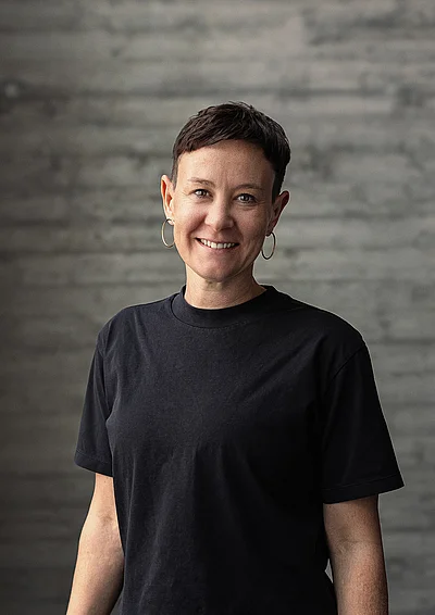 Portrait von Katharina, Teamlead Social, vor einer grauen Sichtbetonwand