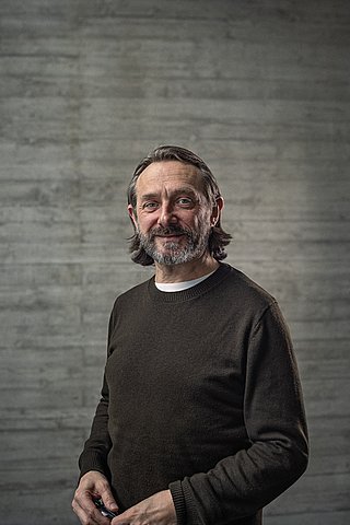 Portrait des Creative-Director Konzept vor einer Sichtbetonwand.