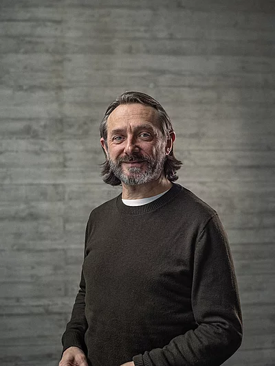 Portrait des Creative-Director Konzept vor einer Sichtbetonwand.