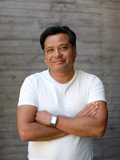 Portrait von Chai Sinthuaree, Geschäftsführer und Inhaber, vor einer grauen Sichtbetonwand