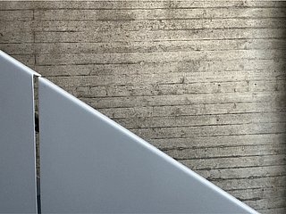 Seitenansicht des Geländers der Metalltreppe im Treppenhaus der Netzbewegung. Im Hintergrund eine Sichtbeton-Wand.